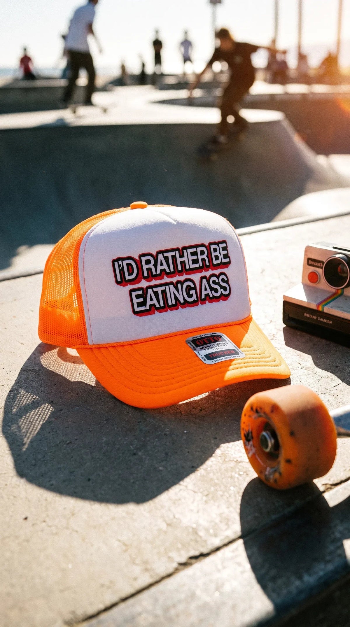 Dirty Merch Apparel neon orange and white trucker hat with bold graphic text on a skate park surface.