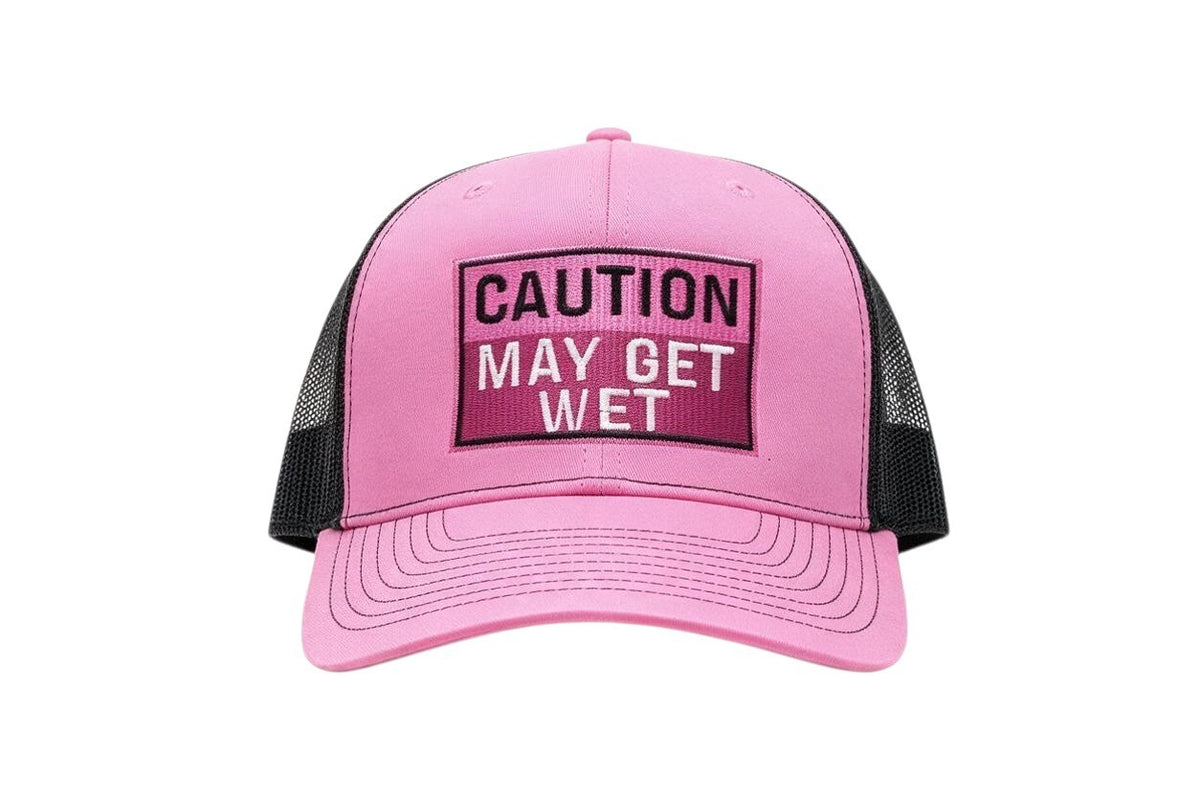 Dirty Merch Apparel pink and black foam trucker hat with embroidered Caution May Get Wet text patch