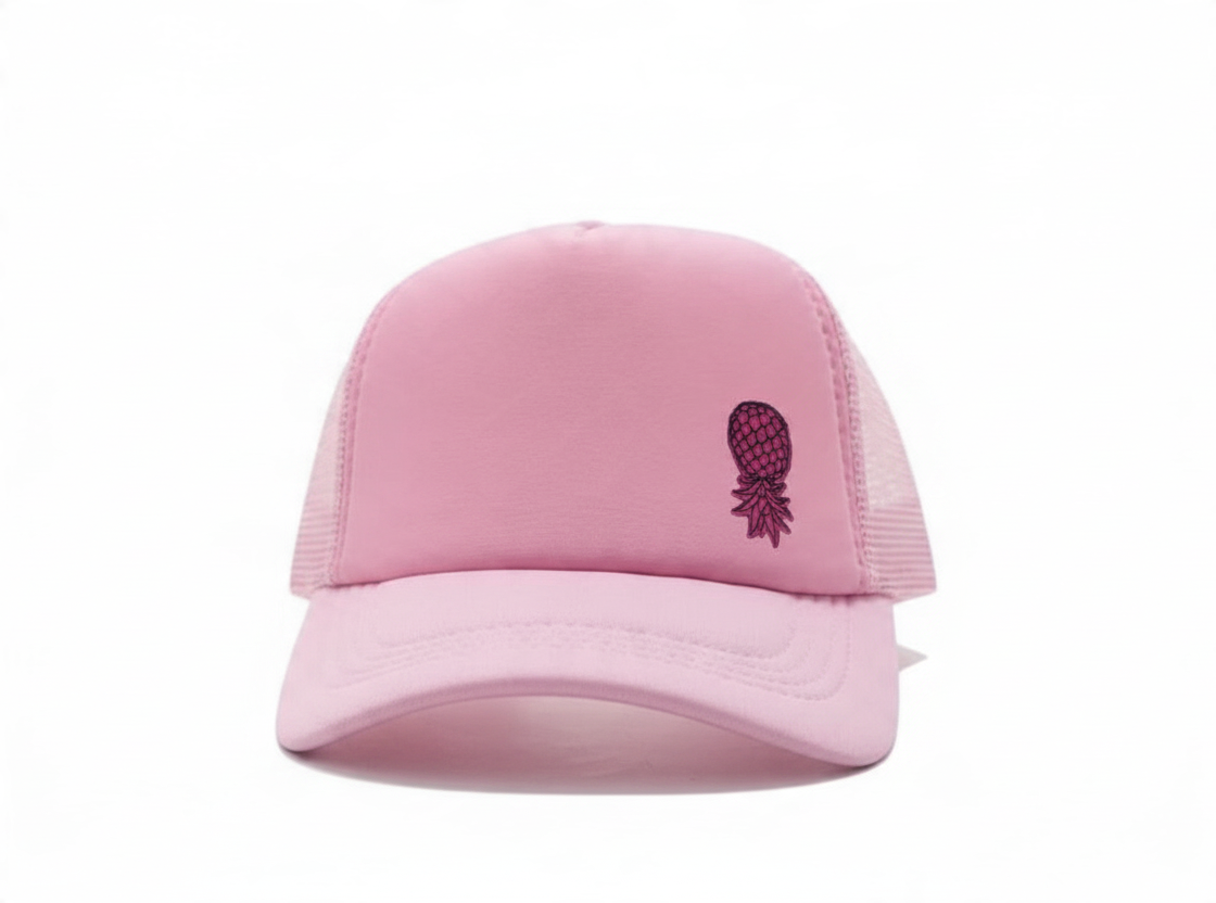 Dirty Merch Apparel light pink trucker hat with a black embroidered pineapple detail and breathable mesh back panel.