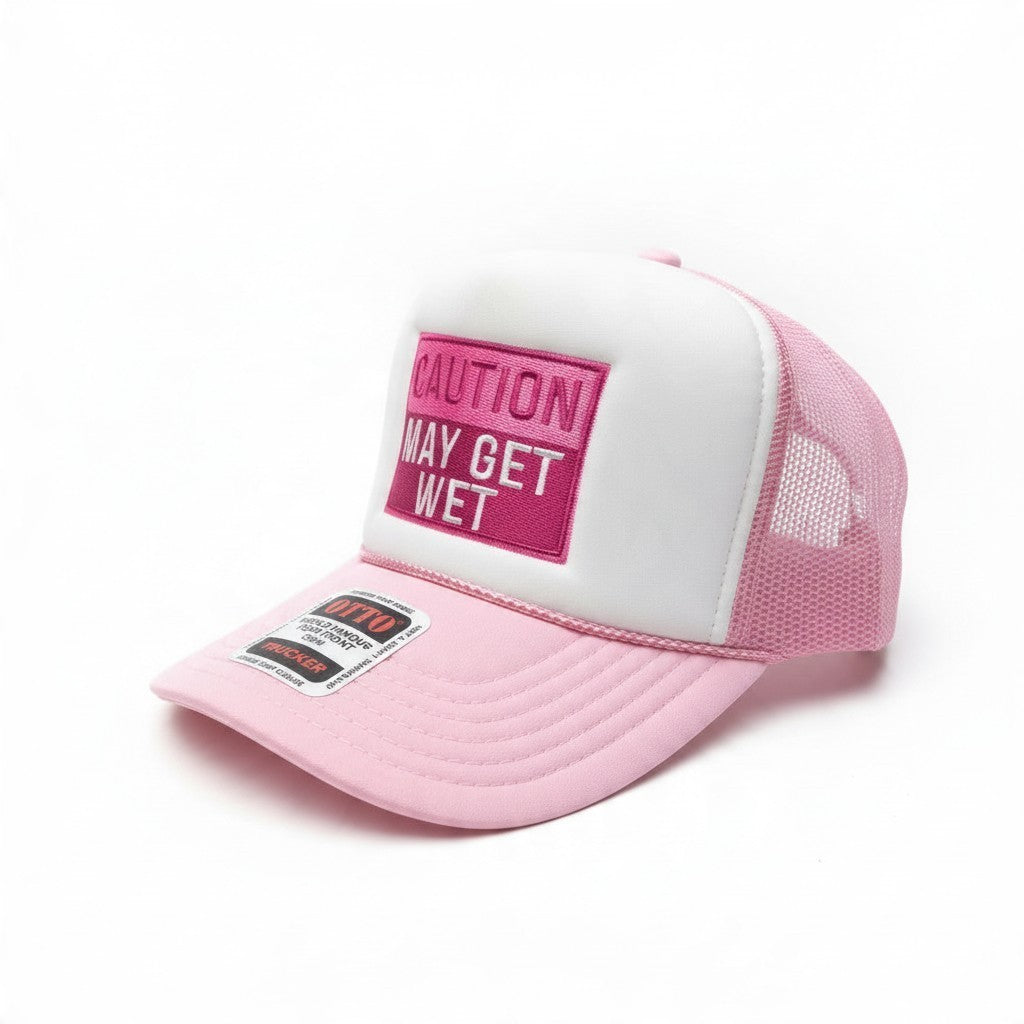 Dirty Merch Apparel pink and white embroidered foam trucker hat with Caution May Get Wet text on a patch